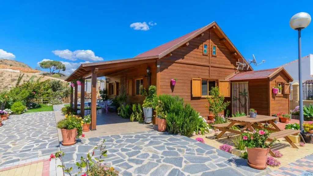 Wooden façade of Casa Alegría, with the entrance porch and potted-plant garden