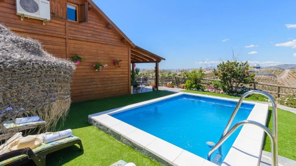 Private pool and garden at Casa Alegría in Almayate Alto, with the wooden house and valley views in the background