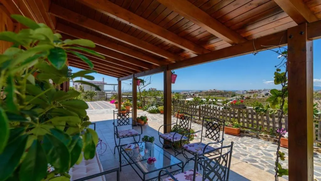 Covered porch at Casa Alegría with a seating area and views towards the coast
