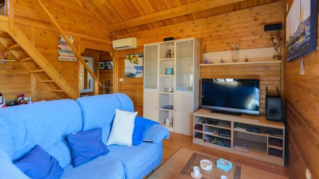 Living room inside Casa Alegría, with sofa, TV and wooden finishes
