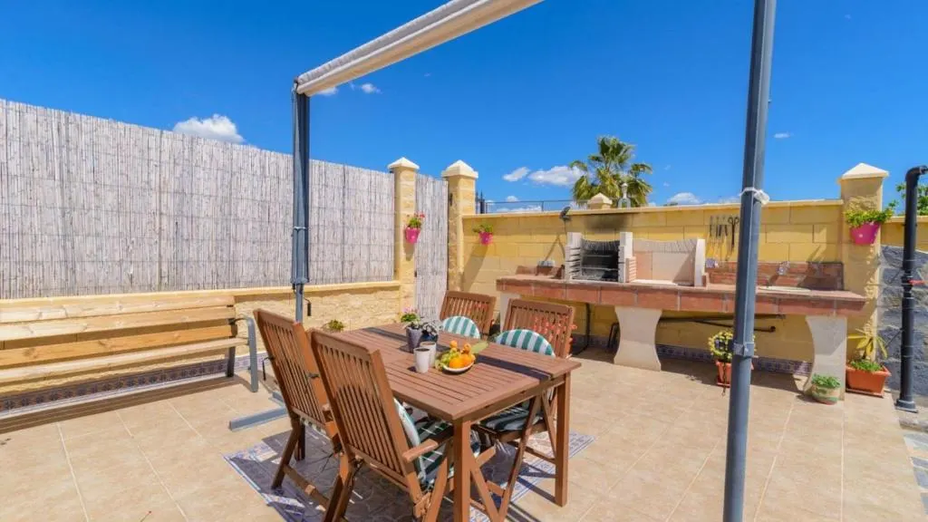 Terrace with a built-in barbecue and outdoor dining table at Casa Alegría