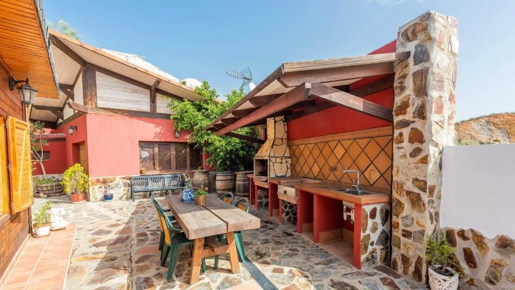 Zona de barbacoa de Cortijo La Tata, con mesa de comedor exterior y encimera de obra