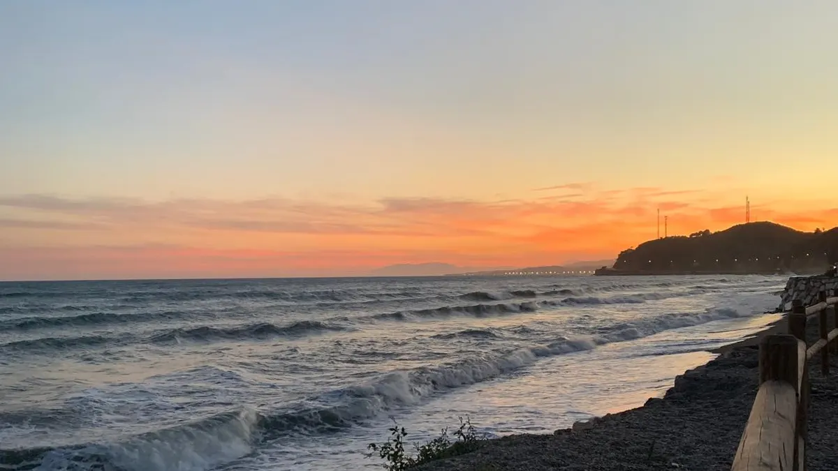 Sunset at Playa de Lagos (Vélez-Málaga), with waves breaking on the shore and the coastline in the background