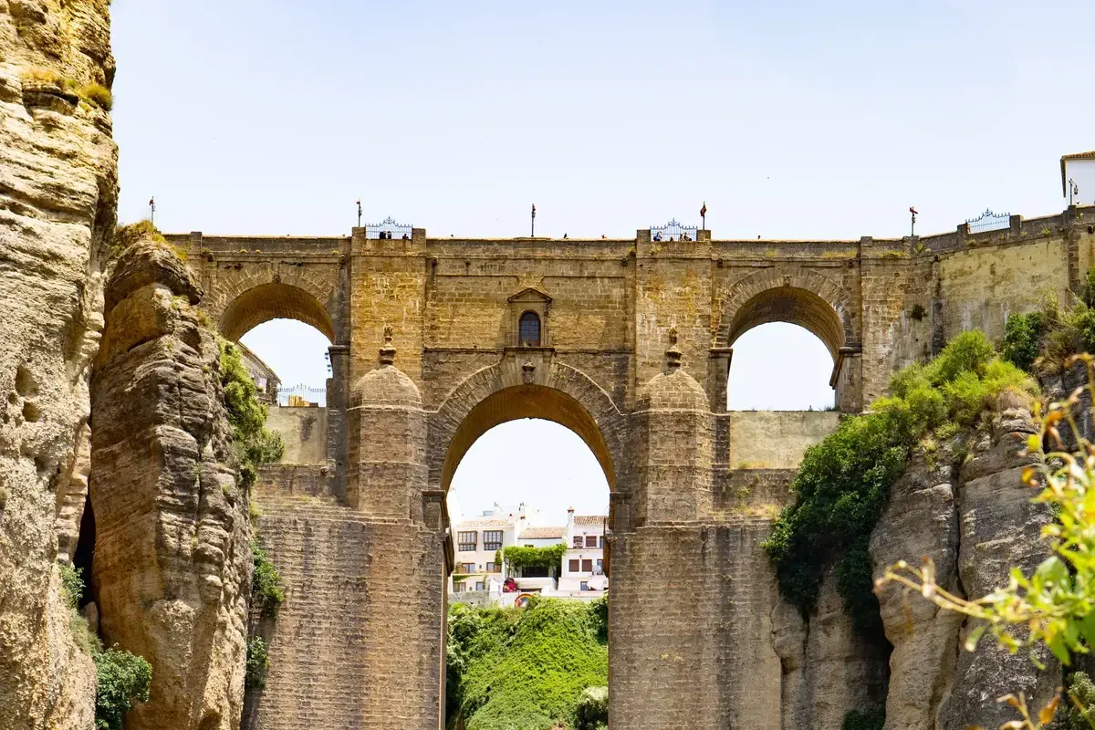 The Puente Nuevo bridge in Ronda up close, with its stone arches over the Tajo gorge and a waterfall in the background